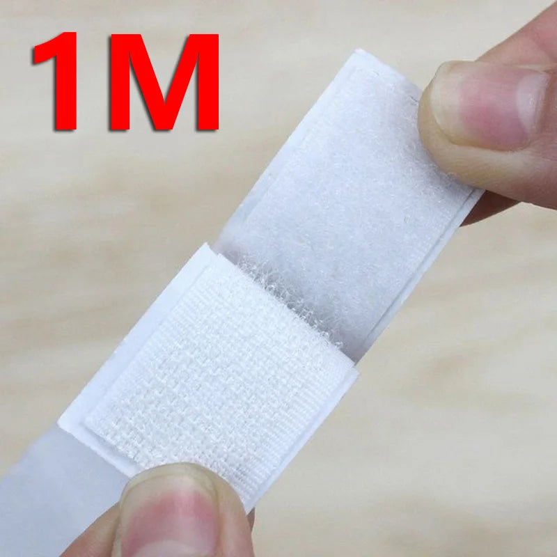 A hand is holding a white self-adhesive hook and loop tape strip, showing its texture and thickness.