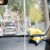A yellow and blue anti-fog glass cleaning sponge resting on a car windshield.
