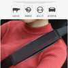 A close-up of a person wearing a red sweater with a black seat belt protector cover visible on their shoulder.