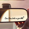 A close-up of a car mirror featuring the Spanish phrase Con Dios todo es posible written in black script.