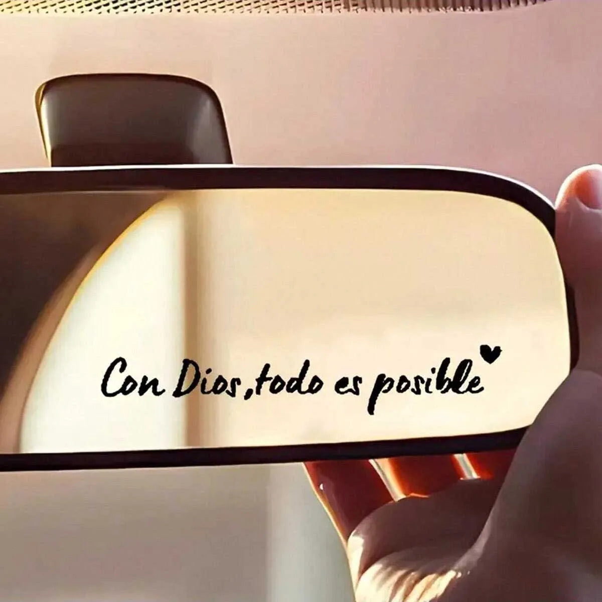 A close-up of a car mirror featuring the Spanish phrase Con Dios todo es posible written in black script.