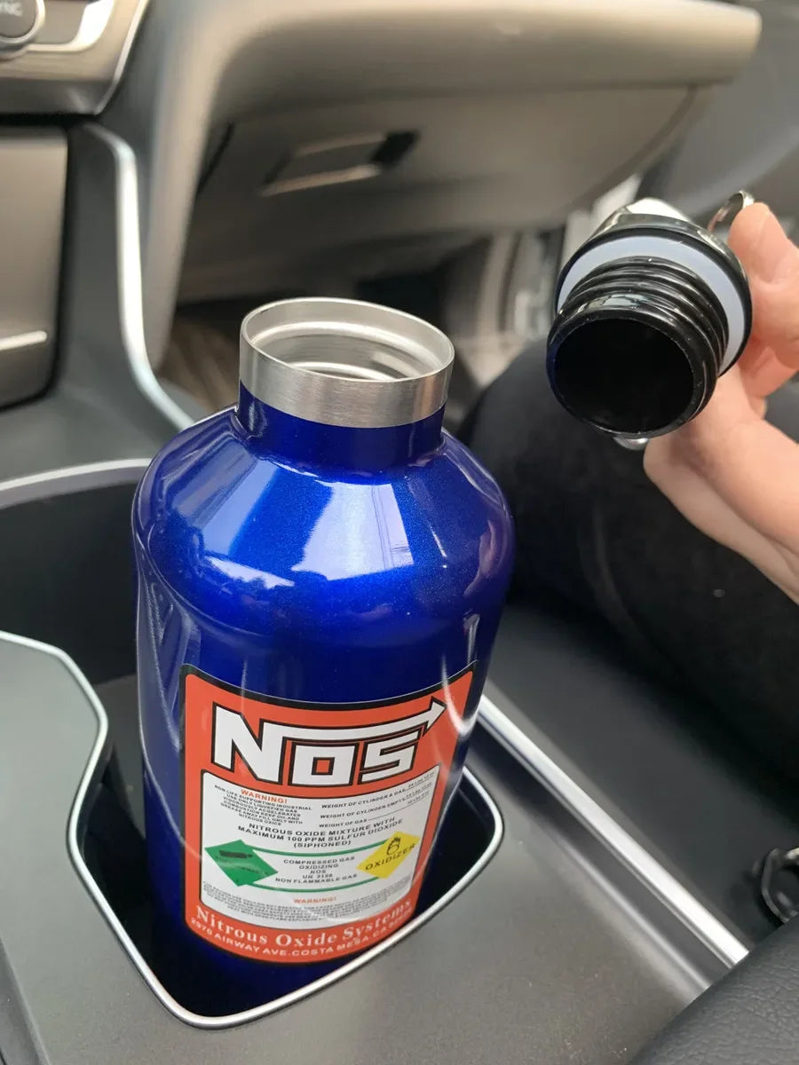 A blue insulated stainless steel travel kettle is placed in a car console.