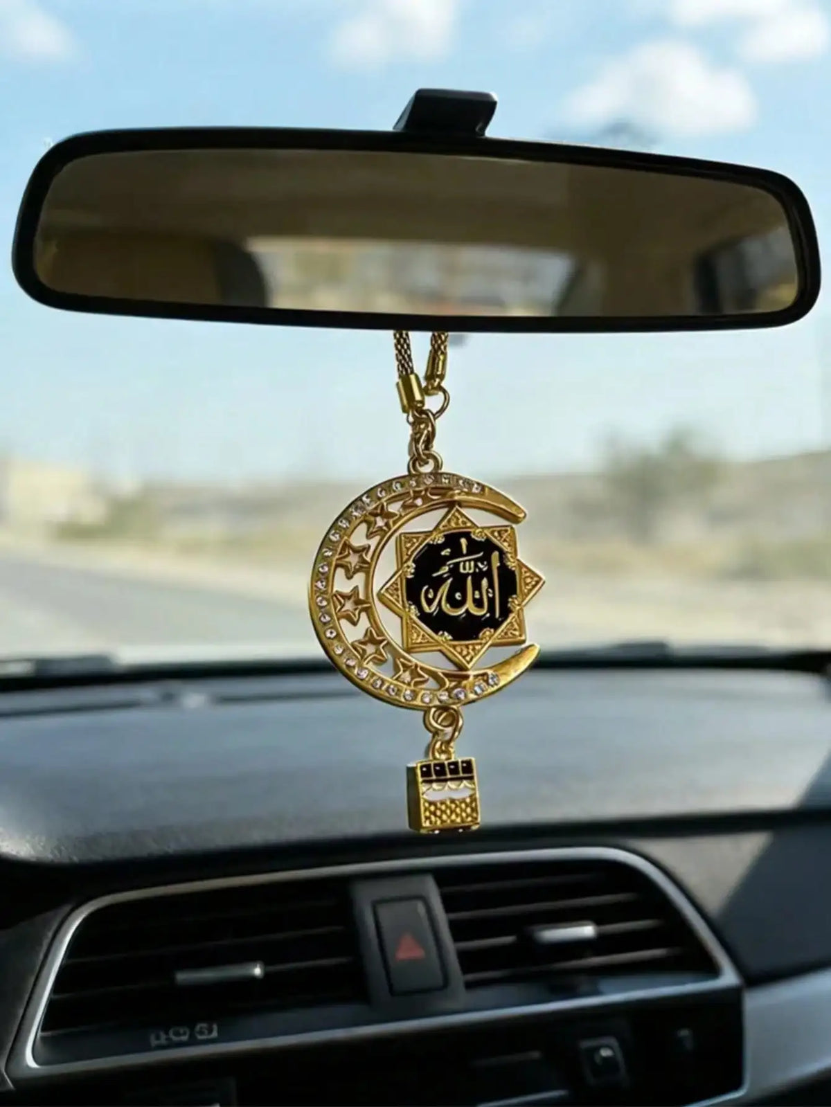 Goldene islamische Kalligrafie-Anhänger in Form eines Halbmondes, hängt am Rückspiegel.