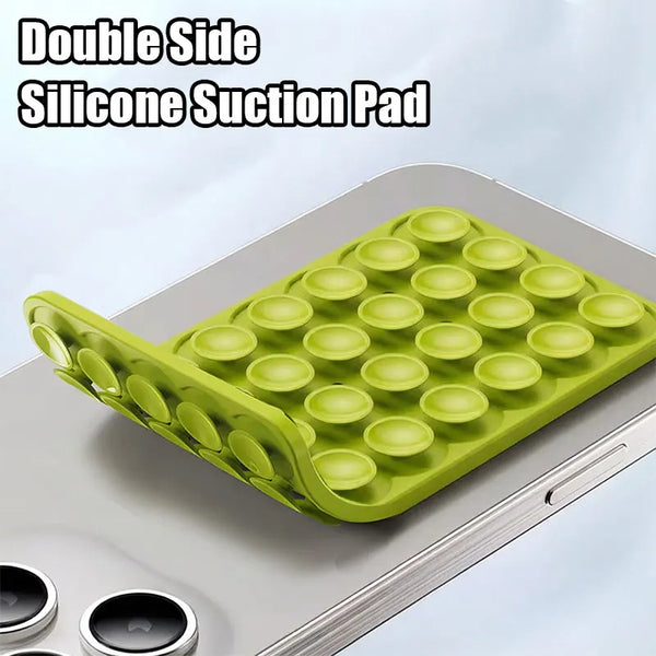 A green silicone suction pad with multiple cups is placed on a silver phone mount.