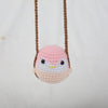 A pink and white crochet hanging bird decor with brown string.