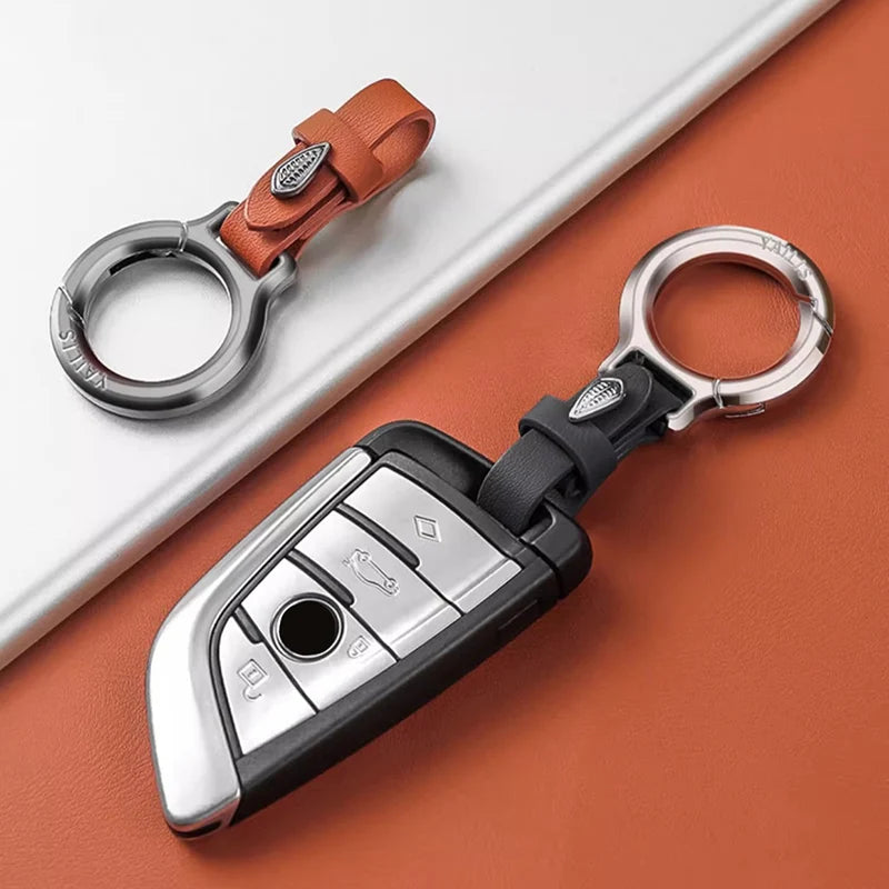 A silver and black leather keychain with a carabiner clip resting on an orange surface.
