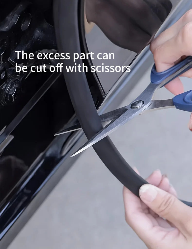 A hand uses silver scissors to cut an excess part from a black car door rubber seal strip.