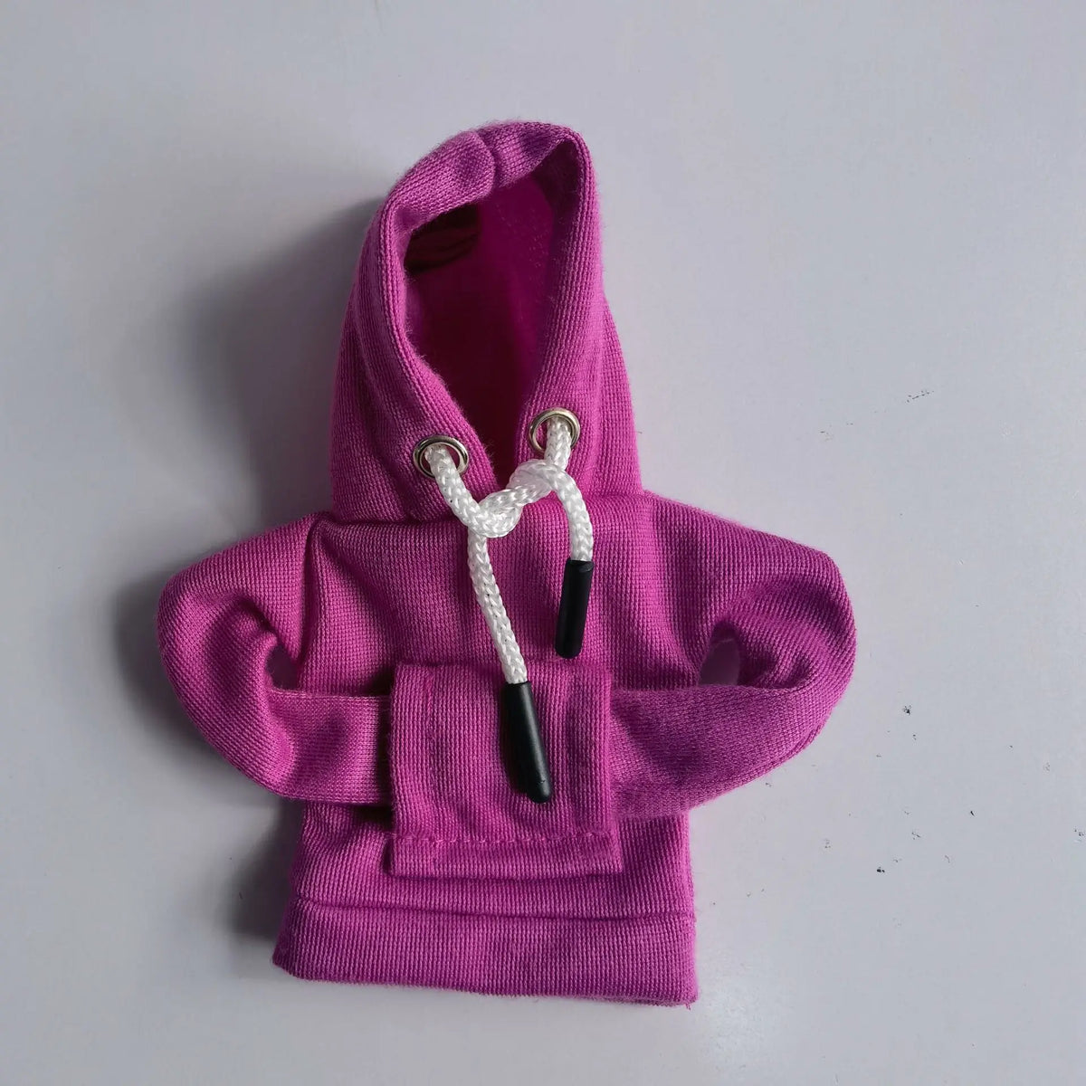 A bright pink hoodie cover with a drawstring detail is displayed on a white surface.