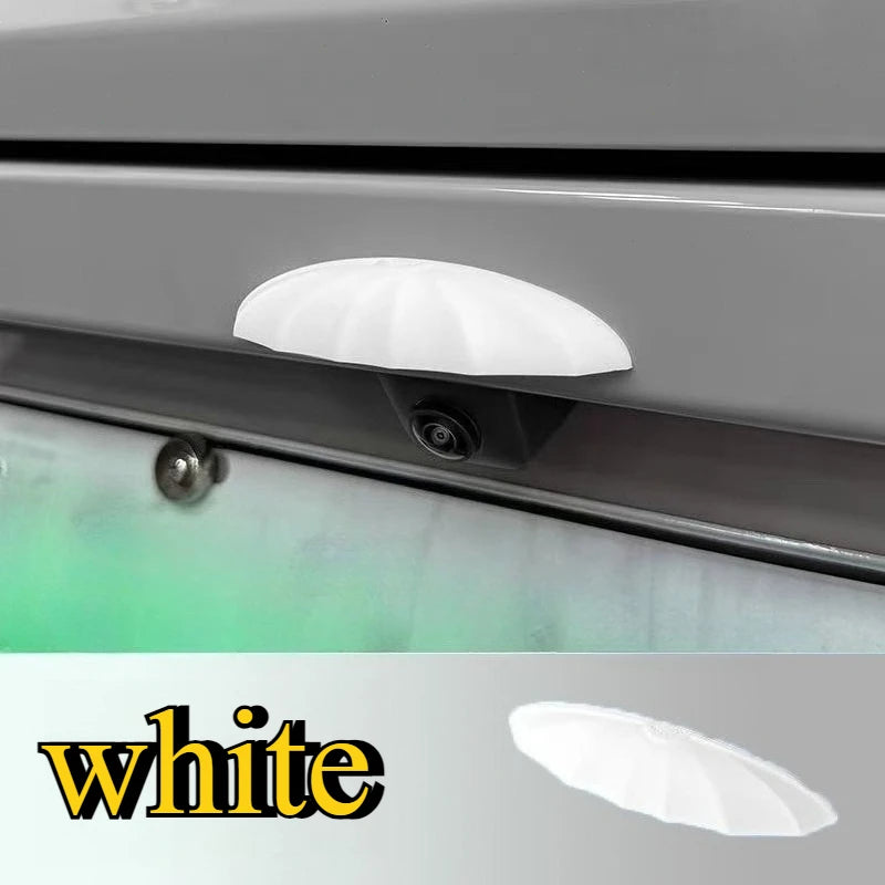 A white universal car rain shield and rear camera cover is shown installed on a vehicle's body panel.