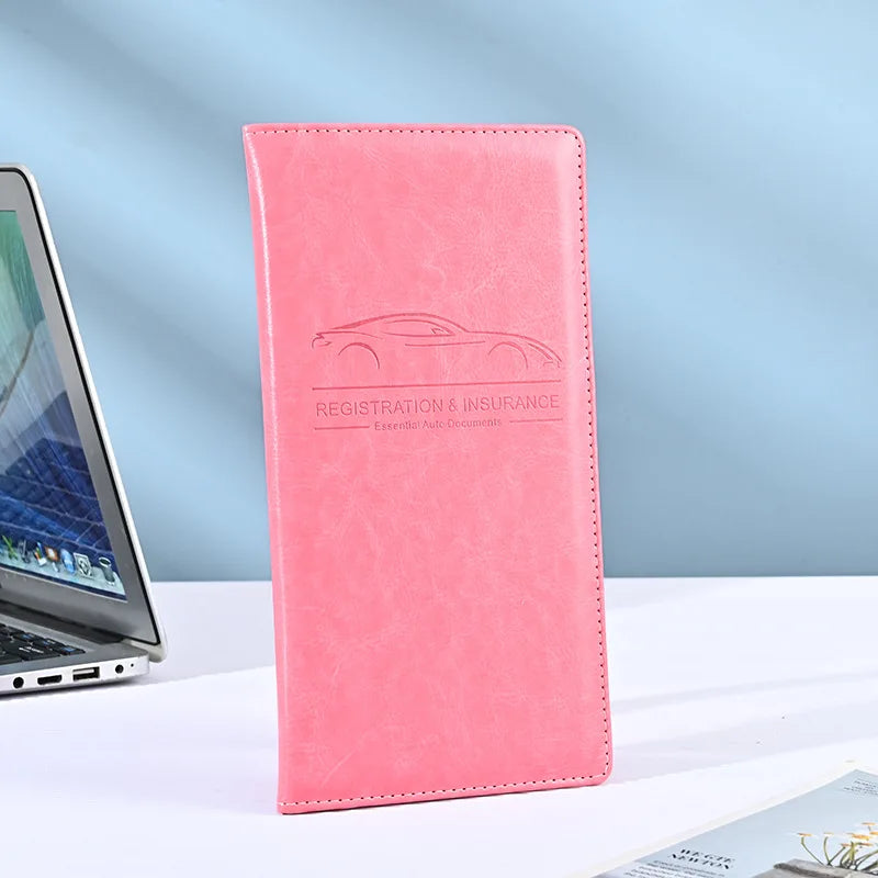 A pink leather vehicle organizer with embossed text for registration and insurance documents.