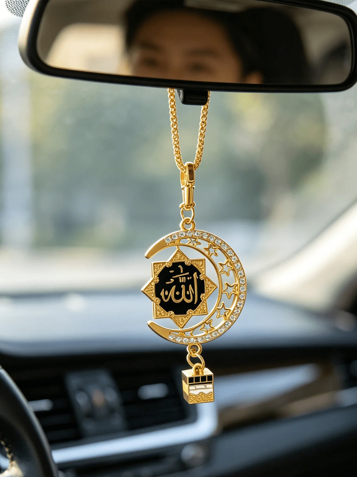 Goldene islamische Kalligrafie-Anhänger mit Stern und Halbmond, hängt an einer Kette, sichtbar im Rückspiegel eines Autos.