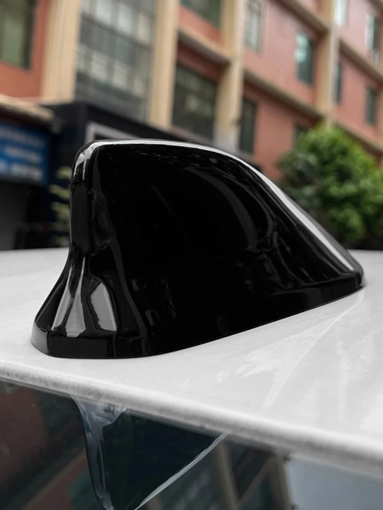 Black shark fin roof antenna cover resting on a white surface.