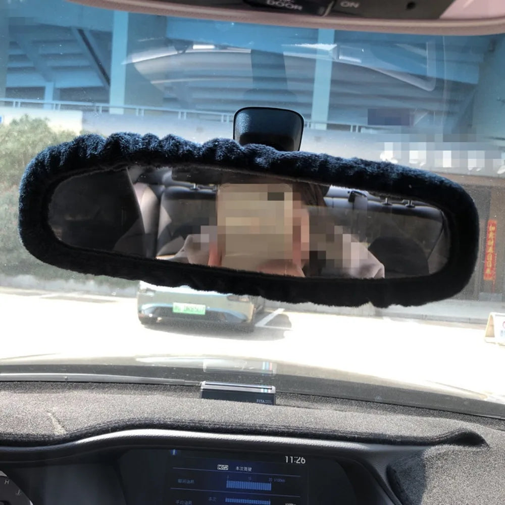 A black fuzzy plush cover is placed over a car's rearview mirror.