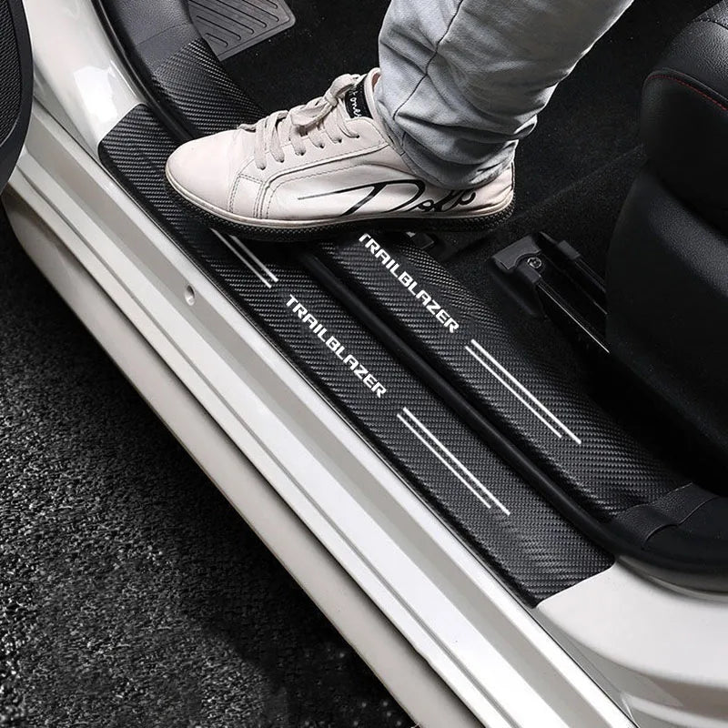 A close-up of a Trailblazer carbon fiber decal protecting a car door or trunk, with a person's shoe visible.