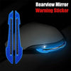 Rearview mirror warning sticker featuring blue reflective strips on a car body.