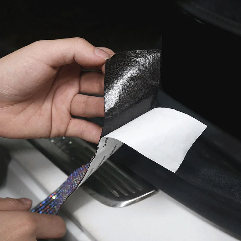 A hand is applying a black decorative diamond trim strip to a car body surface.