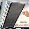 A hand is deploying a black mesh retractable car windshield sun shade in a vehicle interior.