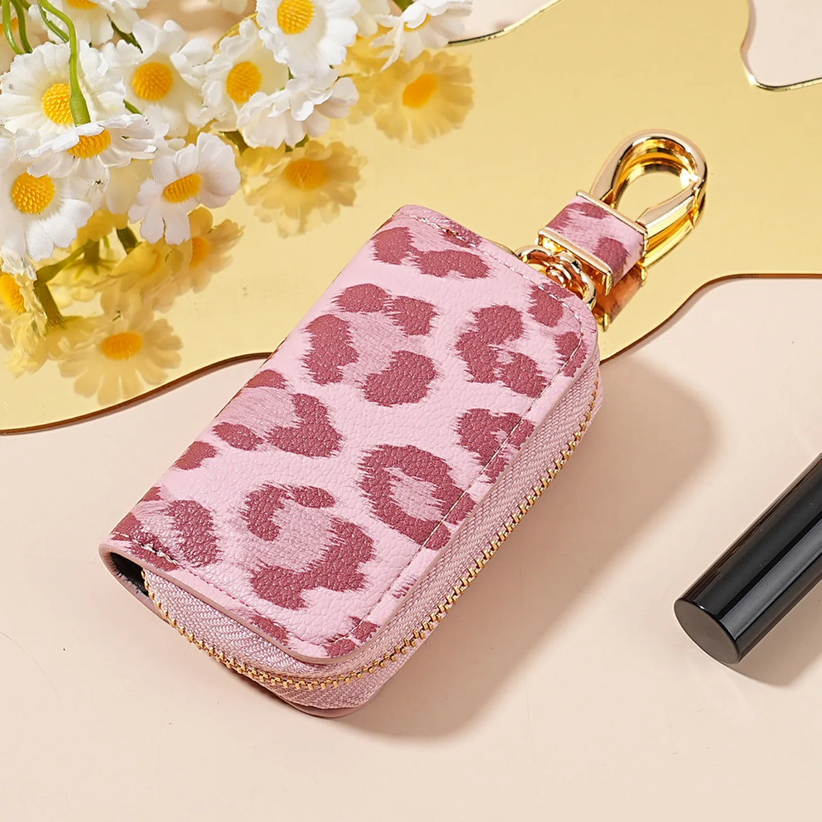 A pink leopard print car key holder with a gold-toned clasp resting on a light background.