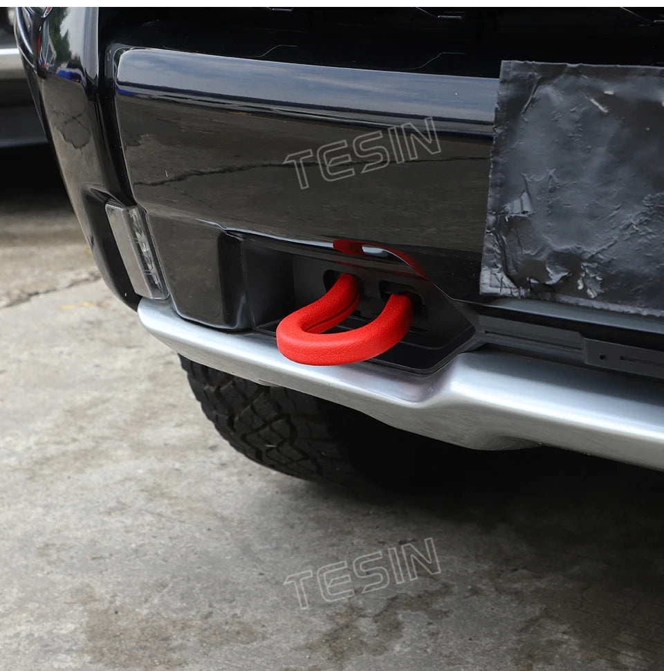 Close-up of a silver car bumper with an orange tow hook cover installed.