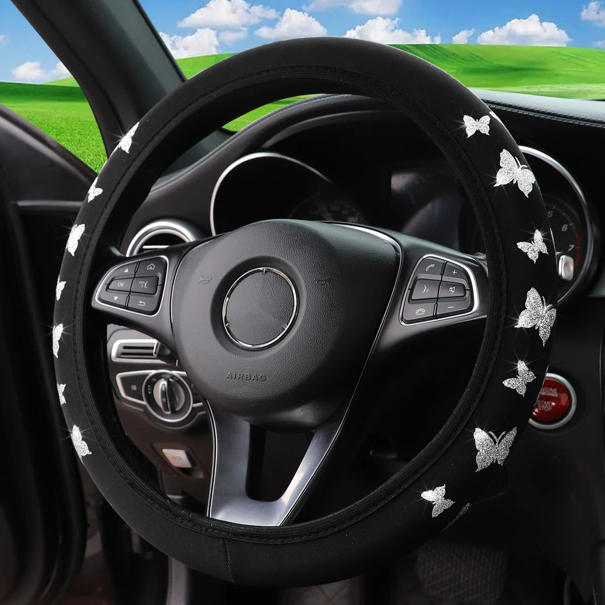 Black steering wheel with a glitter butterfly pattern and controls in a car interior.