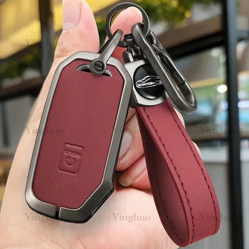 A maroon leather key fob cover with a metal tag and clip is held in a hand.