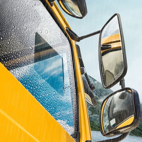 Close-up of a yellow car windshield with raindrops and a clear rearview mirror.