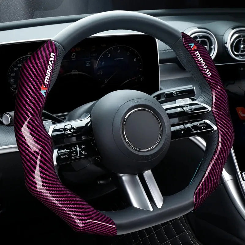A close-up view of a steering wheel covered in black leather and accented with a purple carbon fiber pattern.