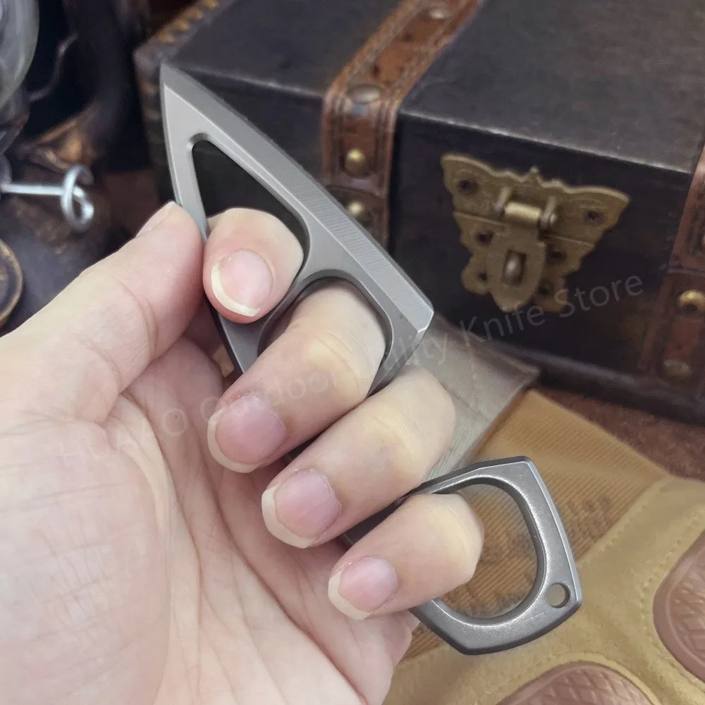 A hand holds a gray fixed blade survival knife next to a leather box.