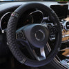 Close-up view of a black embroidered leather steering wheel cover inside a car