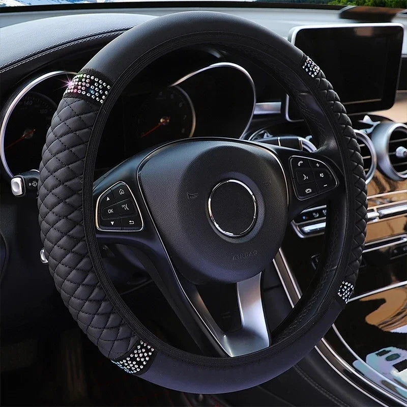 Close-up view of a black embroidered leather steering wheel cover inside a car