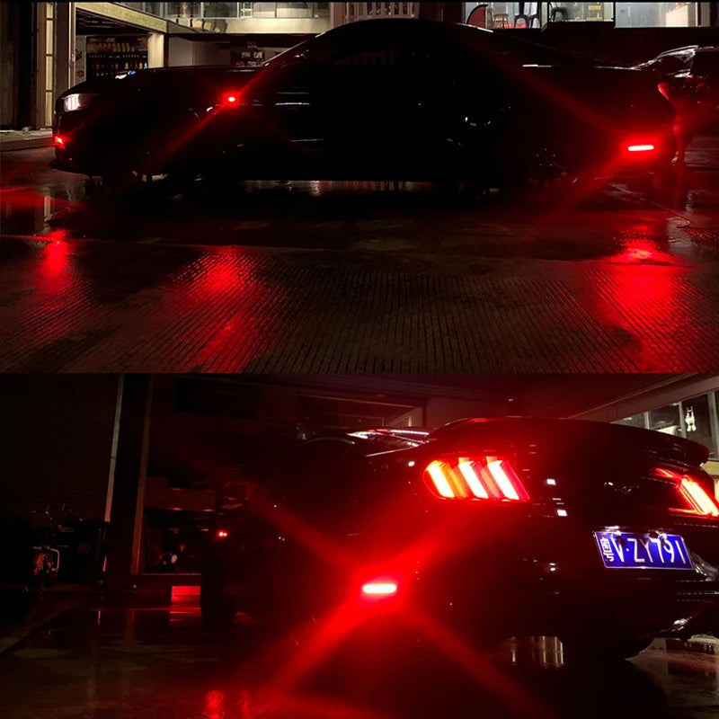 Nahaufnahme der roten LED-Seitenmarkierungsleuchten eines dunklen Autos, die auf nassem Boden reflektieren.