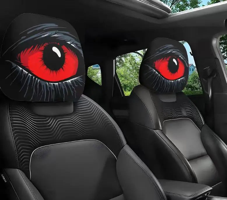 Dos fundas para cabezal de coche negras con llamosos ojos rojos mostradas dentro de la cabina de un vehículo.