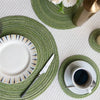 Un ensemble de dessous-de-verre et de sets à couverts tressés ronds vert olive et blanc avec un arrangement floral.