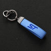 A blue suede leather keychain with a silver clip and a white ST logo etched on the leather strap.