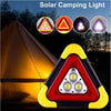 A triangular solar camping light with three LED lights illuminating a tent in the dark.