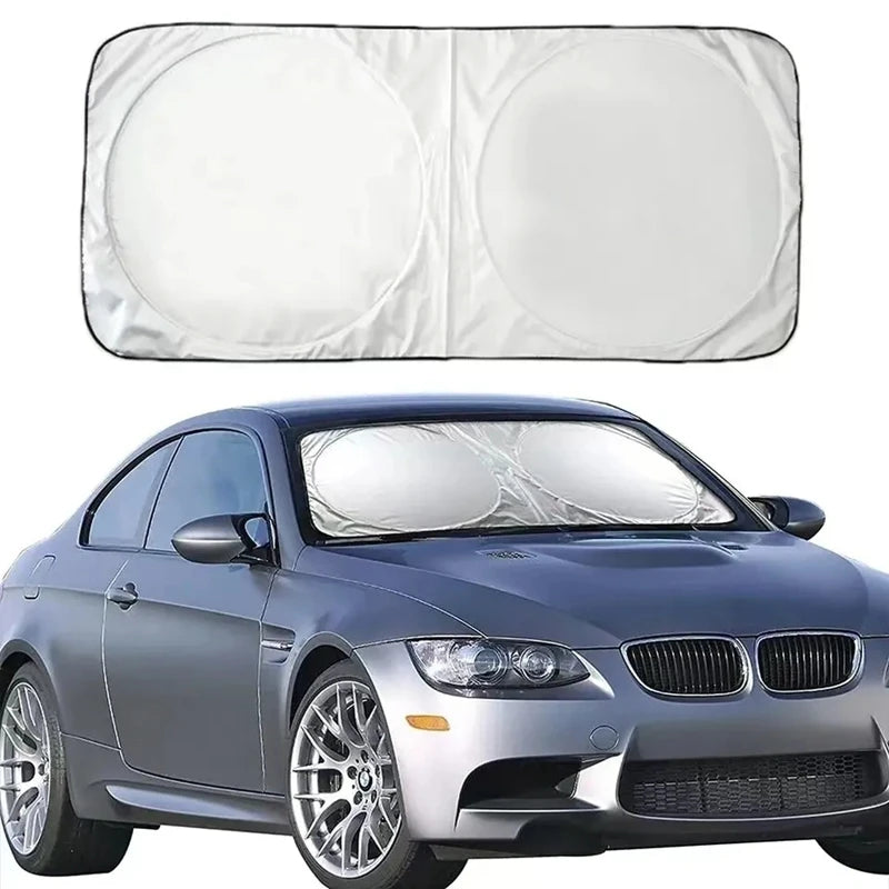 A silver BMW sedan with a clear windshield sun shade visor protector installed.