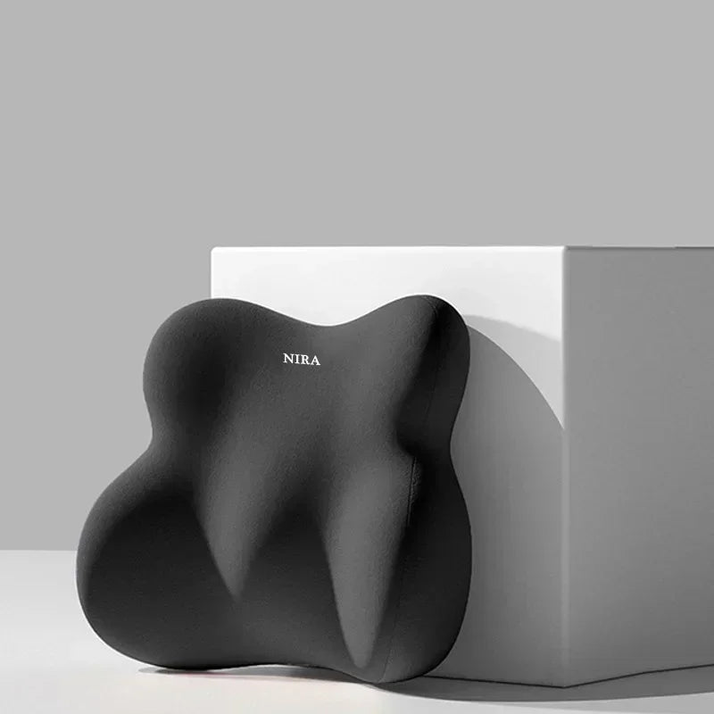 A black ergonomic memory foam pillow shaped for car neck and lumbar support resting on a white box.