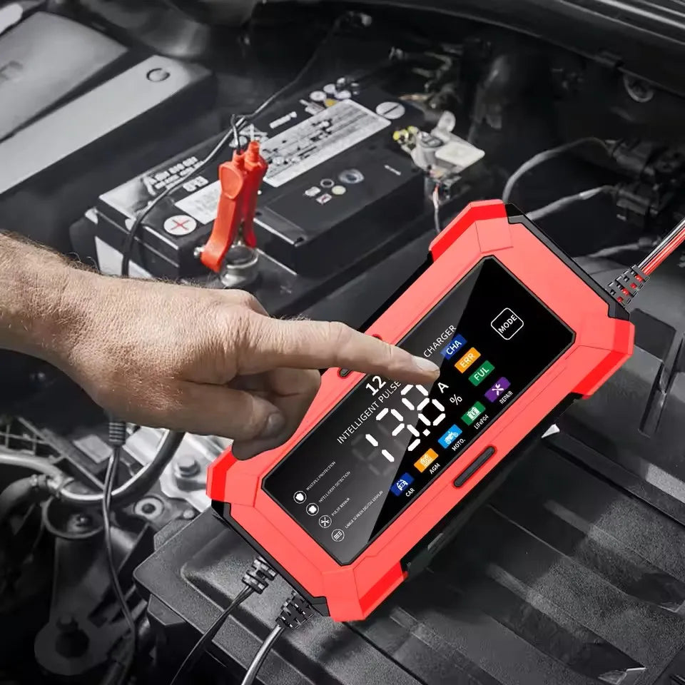 A hand points at a red intelligent car battery charger device placed on a black car interior.