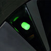 Close-up view of a self-luminous tire valve cap glowing bright green inside a dark device housing.