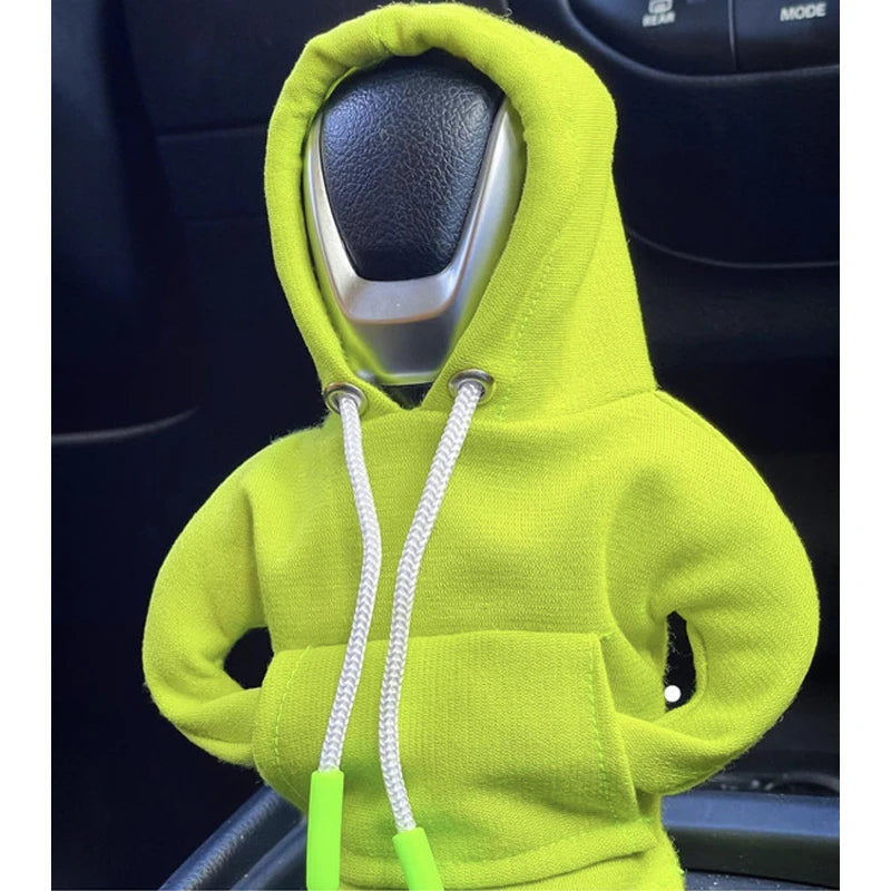 A bright lime green hoodie cover is placed over a car gear shift knob.