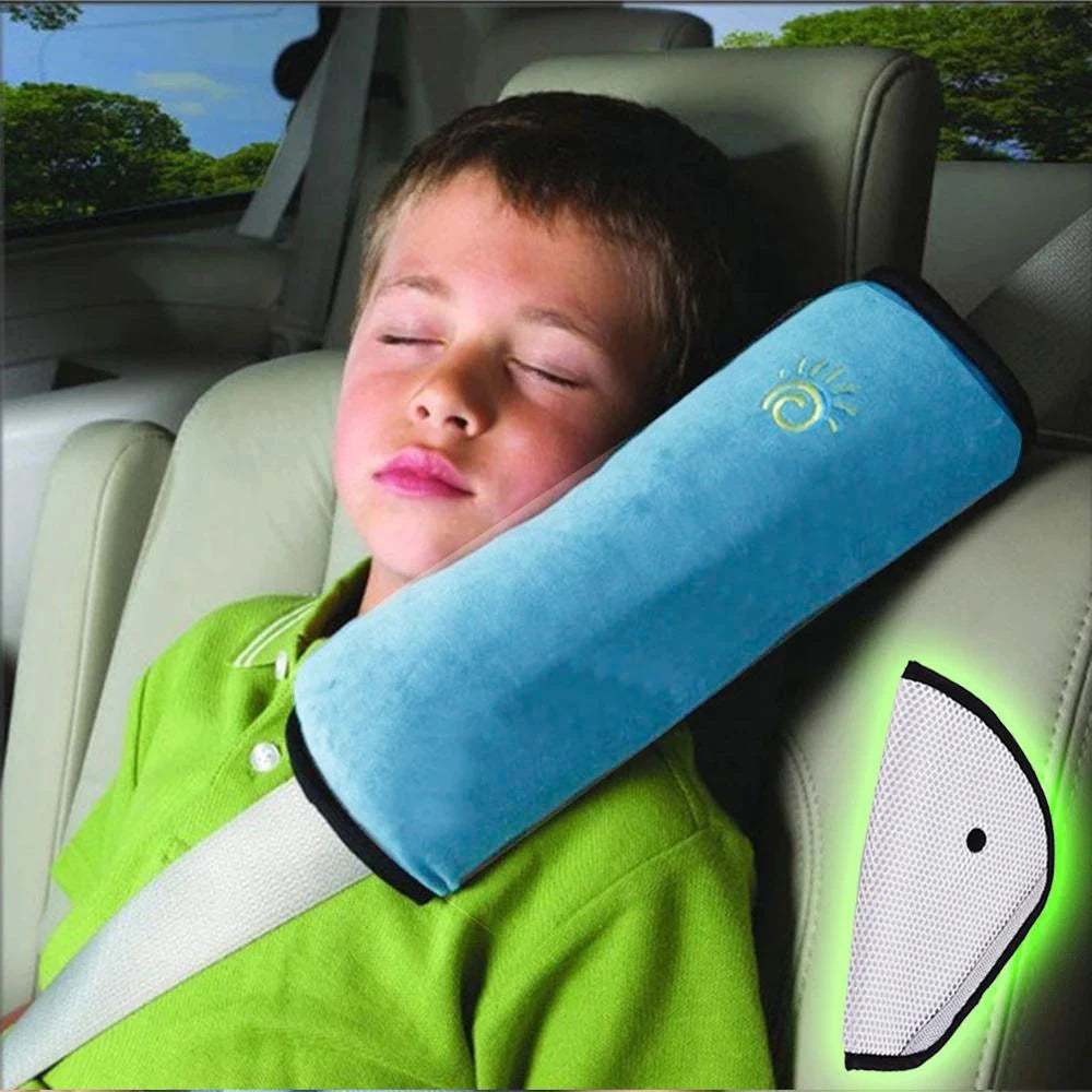 A child is sleeping with a blue shoulder cushion car seat belt placed on their shoulder in a car seat.