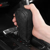 A hand is holding a black artificial leather handbrake cover for a car interior.
