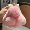 A pink plush bunny keychain with soft fur and a gold ring is held in a hand.