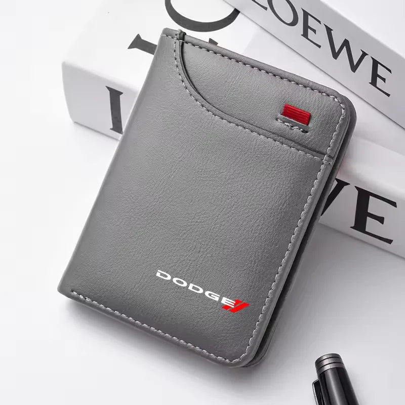 Portefeuille voiture en cuir véritable gris avec accent rouge, posé sur une surface blanche à côté de livres empilés.
