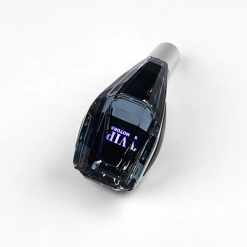 A close-up view of a black LED glowing gear shift knob for a manual transmission car.