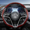Close-up view of a black steering wheel with red carbon fiber texture covers and digital instrument cluster.