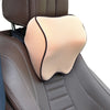 A beige memory foam neck pillow with a black strap is shown in a brown car seat headrest.