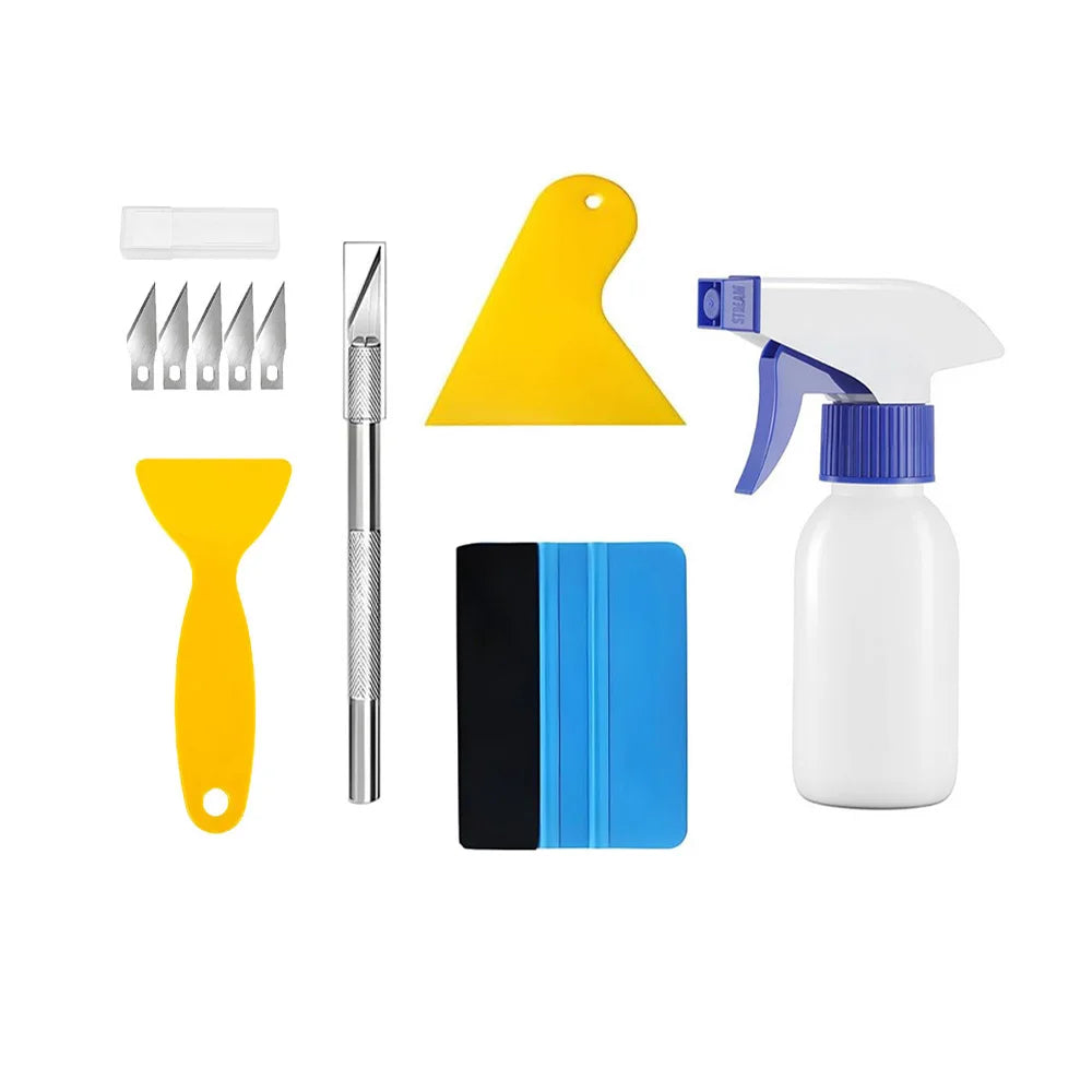 A set of professional automotive film installation tools including a yellow squeegee, a metal blade, and a white bottle.