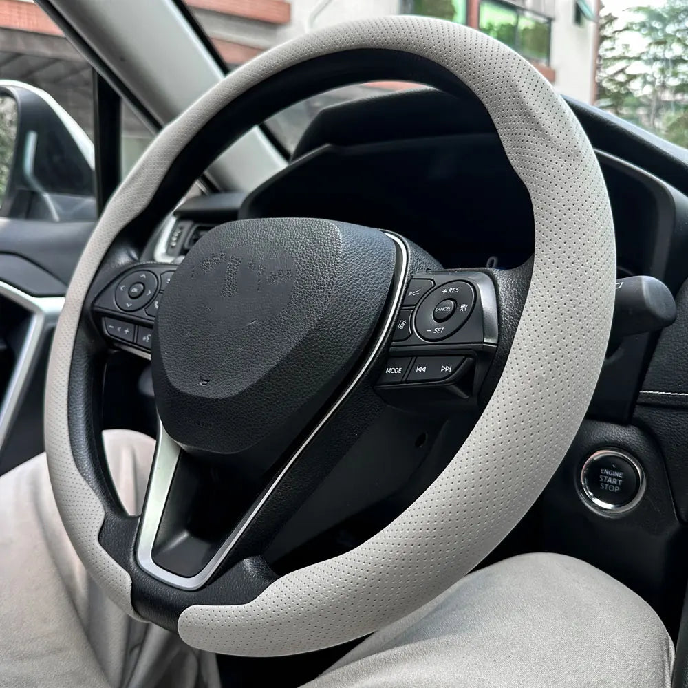 Nahaufnahme eines Lenkrads mit grauer Lederabdeckung in einem Auto.