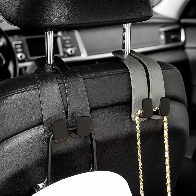 Black car headrest hooks with gold chains used for bag organization.